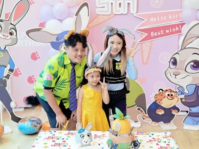 A family of three posing in front of the party backdrop